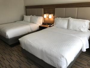 蒙罗维尔Holiday Inn Express & Suites - Pittsburgh - Monroeville, an IHG Hotel的配有白色床单的酒店客房内的两张床