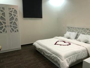塔伊夫شاليه الماسة的一间卧室配有一张白色的床,上面有红色的连衣裙