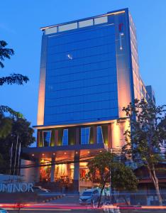 雅加达Luminor Hotel Kota Jakarta By WH的一座大型玻璃建筑,前面有停车位