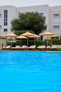 雅典爱斯普瑞希维特尔酒店的一个带椅子和遮阳伞的大型游泳池