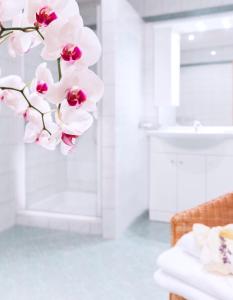 滨湖默尔比施兰德豪斯潘诺尼亚住宿加早餐旅馆的白色浴室设有白色水槽和粉红色兰花