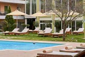 雅典Civitel Attik Rooms & Suites的一座带躺椅和遮阳伞的游泳池位于大楼旁