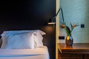 阿莫拉艾维登西亚比华迪酒店的一间卧室,配有一张床和一个花瓶,桌子上放着植物