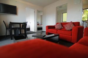 基督城瑞卡顿大都会汽车旅馆的客厅配有红色的沙发和桌子