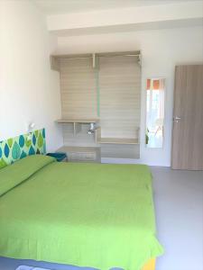 利多迪耶索罗Hotel & Residence Al Mare的一间卧室设有一张绿色的床和一个窗户。