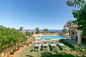 德尼亚Villa Montgo Denia的别墅设有游泳池和庭院家具。