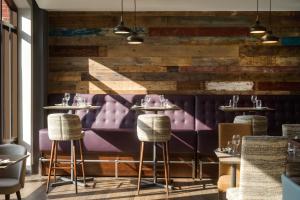 伊普斯威奇诺富特伊普斯威奇中心酒店的餐厅设有紫色座椅和木墙