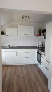 马克特奥伯多夫Christl's Ferienwohnung的白色的厨房配有白色橱柜和木地板