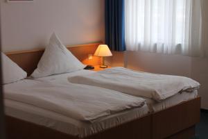 波茨坦莉莉玛莲电影酒店的一张带白色床单的床和一盏靠窗的灯