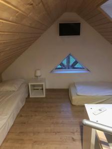 缅济热奇Pensjonat Pod Strzechą的一间卧室设有两张床,墙上配有电视。