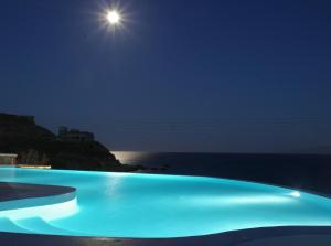 凯勒里瓦迪米科诺斯潘泰恩公寓酒店的夜间游泳池,月亮在海洋上