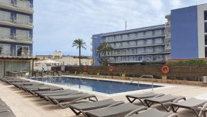 坎布里尔斯凯撒奥古斯都酒店的一座带躺椅的游泳池位于大楼旁