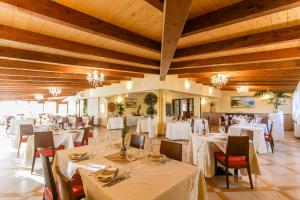 卡布拉斯苏索埃酒店的餐厅设有白色的桌椅和木制天花板。
