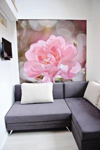 卡梅拉瓦Lofts - Kaunas airport的一张沙发,房间里有一幅粉红色花画