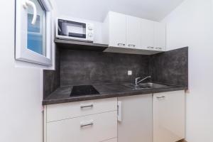 巴什卡沃达Apartments Gavran的厨房配有白色橱柜、水槽和微波炉