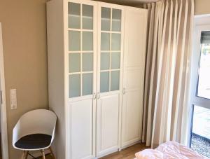 格洛米茨Ferienwohnung Möwennest N°3的卧室内的白色橱柜,配有椅子