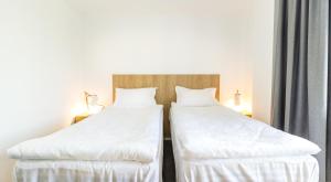 锡比乌Horeum Boutique Hotel的配有白色床单的酒店客房内的两张床