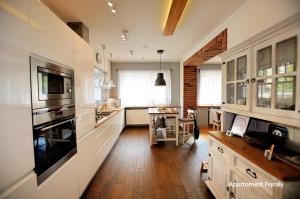 卡托维兹Biały Dom - 2 Bedrooms的厨房铺有木地板,配有白色橱柜。