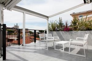 里乔内Meg Lifestyle Hotel & Apartaments的阳台的庭院配有白色的桌椅