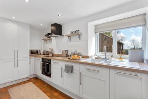 利克Harewood Cottage Peak District的厨房配有白色橱柜、水槽和窗户。