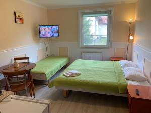 德兹维济诺Apartamenty i Pokoje Magnolia的客房设有两张床、一张桌子和电视。