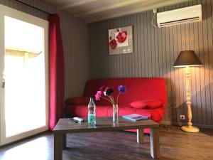 拉萨尔韦塔Domaine de Label, Spa, massages的客厅配有红色的沙发和带鲜花的桌子