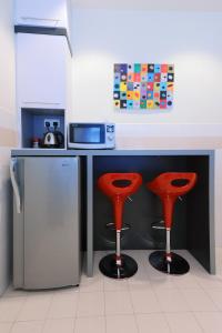 马六甲The One Vacation Home的厨房配有带两个红色凳子的柜台