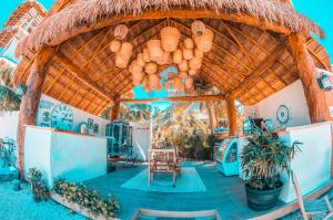 奥尔沃克斯岛Ensueño Holbox & Beach Club的一座带茅草屋顶的建筑,配有桌椅