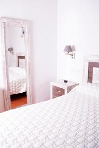 卡皮雷拉维斯塔卫莱达公寓酒店的一间白色卧室,配有两张床和镜子