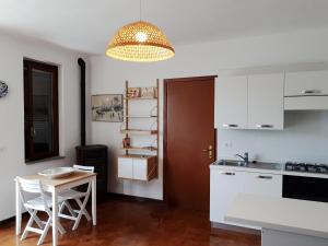 里奥内莱尔巴Nisportino的厨房配有白色橱柜、桌子和吊灯。