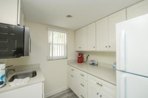 萨拉索塔Siesta Key Beach Resort and Suites的厨房配有白色橱柜、水槽和冰箱。
