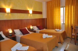 罗列特海岸Hostal - Pensión El Amigo的酒店客房,设有3张带黄色窗帘的床