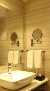 瓦皮Regenta Central Harsha Vapi的浴室配有水槽、两面镜子和毛巾