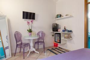 维罗纳Giardino Giusti House & Court的一间设有两张紫色椅子、一张桌子和一台电视的房间