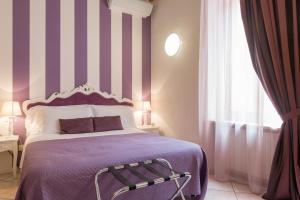 维罗纳Giardino Giusti House & Court的一间卧室配有一张带条纹墙的紫色床