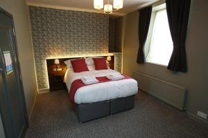 罗斯伯里The Queens Head Hotel的一间卧室配有一张带红色枕头的床和一扇窗户