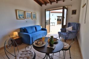 AnaphotiaSamareitidos Light Cottage的客厅配有蓝色的沙发、桌子和椅子