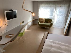 路德维希堡hotelmärchen Garni的一间卧室配有书桌、椅子和电视。