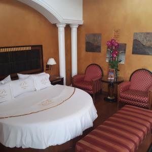 墨西哥城Villas Princess Hotel的酒店客房,配有一张床和两把椅子