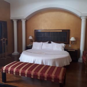 墨西哥城Villas Princess Hotel的卧室配有白色大床和长凳