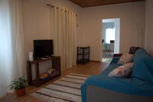 Lajes das FloresCasa da Guida的客厅配有蓝色的沙发和电视