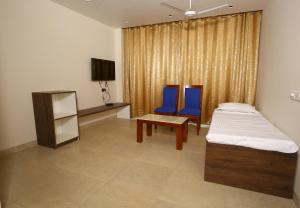 马图拉Hotel Manbhavan的一间卧室配有2把蓝色椅子和1张床及桌子