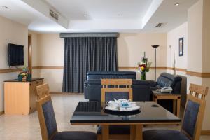 麦纳麦伯伊尚国际酒店 的客厅配有桌椅和沙发