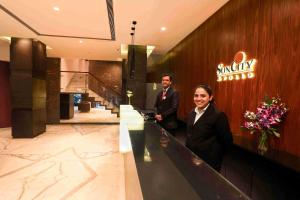 孟买Hotel Suncity Apollo, Colaba的站在酒店大堂柜台的男女