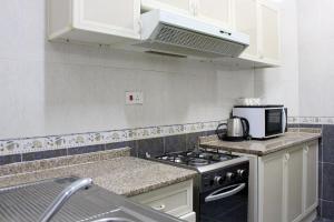 马斯喀特撒哈拉公寓酒店的厨房配有炉灶和微波炉。