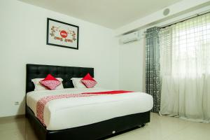 巴东OYO 882 Puri Gevana Guest House的一间卧室配有一张带红色枕头的大床