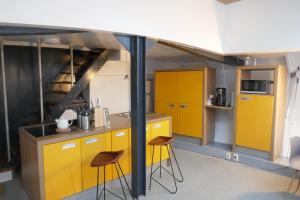 鹿特丹Boathotel Rotterdam Wilhelmina的厨房配有黄色橱柜和2张凳子