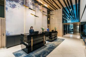 曼谷The Key Premier Hotel Sukhumvit Bangkok的两个人站在大堂的桌子旁