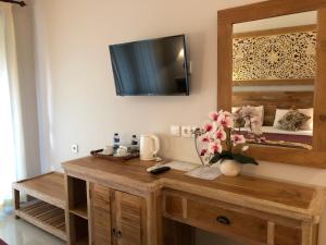 乌布巴厘岛贝图图别墅旅馆的客房设有木桌,墙上配有电视。
