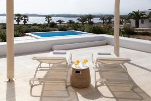 圣玛丽亚The Sand Collection Villas的一个带两把椅子和一张桌子的庭院和一个游泳池